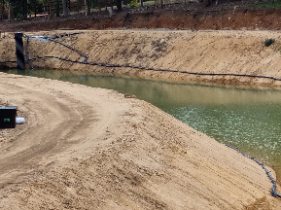 A dam excavation with graded banks and water settling in the base