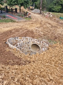 A finished circular sandstone retaining wall around a drainage culvert pipe