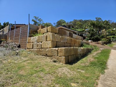 A tall stepped sandstone retaining wall built around a corner