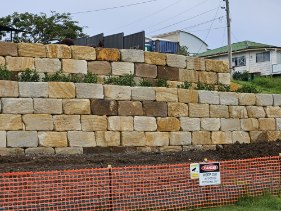 A long sandstone retaining wall along a street frontage